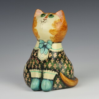 Joan and David de Bethel, a papier mache figure of a seated cat with green glass eyes, dressed in a green and floral dress and booties with verse to back, marked  Made for Herbert Johnson of London by Joan and David De Bethel, Rye, Sussex, dated 1968, 22cm 