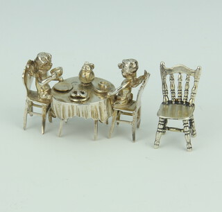 A cast silver model of 2 angels sitting at a table laid for tea together with a chair 41.5 grams, 5cm