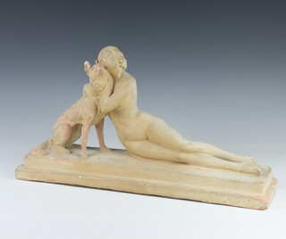 A ceramic moquette of a reclining naked lady cuddling an alsatian, raised on a rectangular plinth  50cm