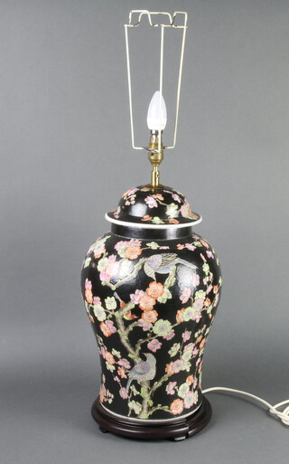 A Chinese black ground vase and cover decorated with birds and peony 45cm, converted to electricity with a hardwood stand (a/f) 