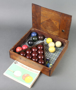 17 various billiard balls comprising 11 brown, 2 red, 1 blue, 1 green, 1 black, 4 cue balls, all contained in an oak case 8cm x 22cm x 31cm  