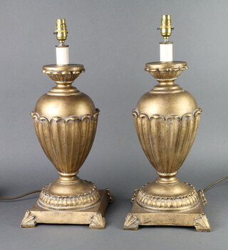 A pair of gilt resin table lamps of urn form and leaf decoration, raised on square bases, 43cm h x 23cm w x 22cm d 