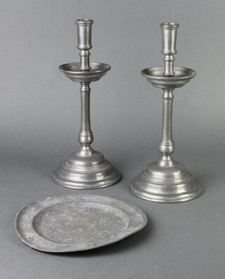 A pair of 17th Century style Continental pewter candlesticks, the bases marked SS Cosma Et Damianus 1677, the base with 4 touch marks, 32cm h x 14cm, together with a pewter plate marked London and with touch mark 22cm diam.  