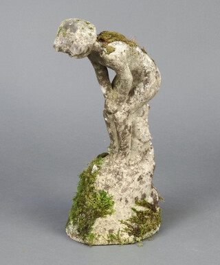 A well weathered reconstituted garden stone figure of a standing child on a rocky outcrop 50cm h x 21cm d x 18cm d 