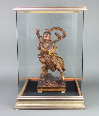 An Eastern carved hardwood figure of a standing immortal 40cm h x 18cm w x 16cm d, contained in a glazed display cabinet 58cm h x 45cm w x 42cm d 