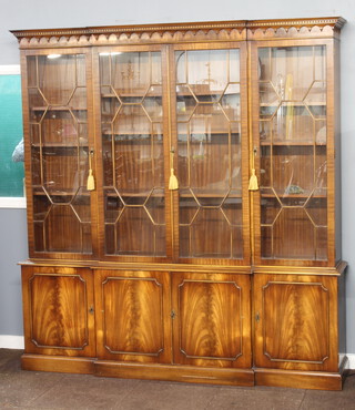 A Chippendale style mahogany breakfront display cabinet on cabinet, the upper section with moulded and dentil cornice, fitted shelves enclosed by astragal glazed panelled doors, the base fitted triple cupboards, raised on a platform base 125cm h x 202cm w x 40cm d 