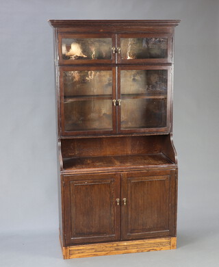 An oak and Globe Wernicke style 4 tier bookcase, the upper section with moulded cornice above a cupboard enclosed by panelled doors, further cupboard enclosed by panelled doors with recess above a fitted cupboard enclosed by panelled doors, raised on an associated base 116cm h x 89cm w x 39cm d  