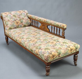 A late Victorian oak show frame chaise longue with bobbin turned decoration, upholstered in floral material, raised on turned supports 68cm h x 183cm l x 64cm d