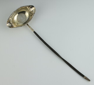 A Georgian white metal whalebone ladle with coin set base 