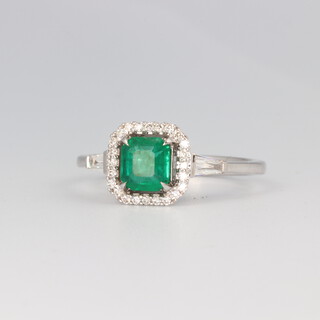 An 18ct white gold Art Deco style emerald and diamond cluster ring, the square cut emerald 0.97ct, the brilliant cut diamonds 0.12ct and the 2 tapered baguette cut diamonds 0.15ct, 4.1 grams, size O 1/2