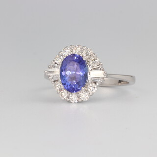 An 18ct white gold oval tanzanite and diamond cluster ring, the centre stone 1.54ct, the tapered baguettes approx. 0.15ct and the brilliant cut diamonds 0.42ct, 3.5 grams, size N 