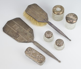 A silver backed engine turned hand mirror and hairbrush Birmingham 1945, 5 mounted toilet jars 