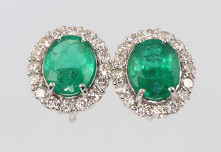 A pair of 18ct white gold oval emerald and diamond pierced ear studs, the emeralds 2.96ct, the brilliant cut diamonds 0.8ct, 4.2 grams 
