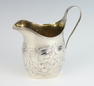 A George III silver repousse helmet shaped cream jug decorated with fruits, having a vacant cartouche London 1800, 118 grams, 13cm 