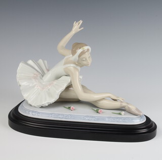 A Lladro figure of a seated ballerina with flowers before her designed by P Perez no.1693.6614 on a wooden plinth boxed, 28cm  
