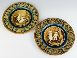 A pair of Austrian wall plates decorated with panels of children enclosed by flowers 31cm 