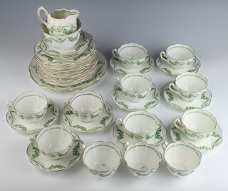 An Edwardian Alfred B Pearce tea set comprising 12 tea cups, 12 saucers, 12 small plates, 2 serving plates, sugar bowl and cream jug decorated with scrolling green flowers  