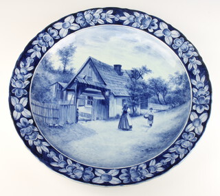 A Delft wall plate decorated with figures before a cottage 39cm