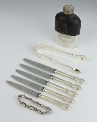 A silver plated mounted hip flask, a pair of silver sugar tongs, 5 butter knives and a moonstone bracelet