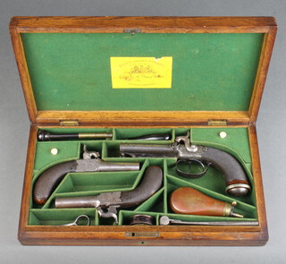 An early 19th century (1813-55) cased set of three percussion pistols comprising a double barrelled pistol and 2 muff pistols, all with Birmingham view and company mark. The double barrel side hammered pistol marked "Sargant Brothers" with stirrup ramrod, chequered walnut butts, blued engraved finger guard. The muff pistols with engraved side plates and chequered walnut butts together with a Sykes powder flask, steel bullet mould, percussion cap box W.E. of London, nipple key and cleaning rod. All contained in a fitted oak case and in good working order