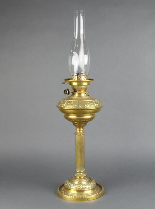 A Victorian embossed brass oil lamp reservoir raised on a reeded column and circular base complete with clear glass shade 45cm h x 19cm 