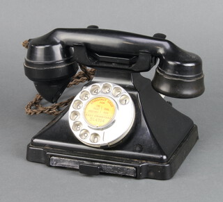 A black Bakelite dial telephone raised on a rectangular outswept base 12cm h x 18cm w x 13cm d 