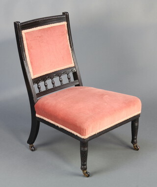 A Victorian ebonised nursing chair with bobbin turned decoration, the seat and back upholstered in pink material, on turned supports  30cm h x 38cm w x 45cm d (seat 30cm x 34cm) 
