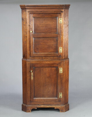 A Georgian oak double corner cabinet, the upper section with moulded cornice and cupboard enclosed by a panelled door, the base enclosed by a panelled door, raised on bracket feet 160cm h x 73cm w x 51cm d 