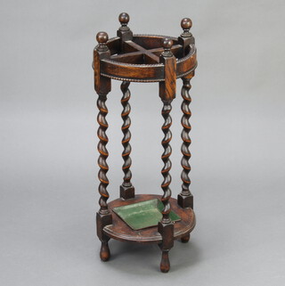A 1930's circular oak, 4 division, umbrella stand with spiral turned columns and complete with drip tray 71cm x 29cm  