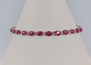 An 18ct white gold oval ruby and diamond bracelet, the rubies 12.23ct, the diamonds 0.55ct, 9.2 grams, 18cm 
