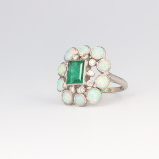 An Art Deco white metal diamond, emerald and opal ring comprising 10 opals each 0.25ct and 10 brilliant cut diamonds each 0.02ct, the emerald cut emerald 1.25ct, size W, 6 grams 
