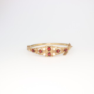 A Victorian style 9ct yellow gold garnet and seed pearl bangle, 18 grams gross 