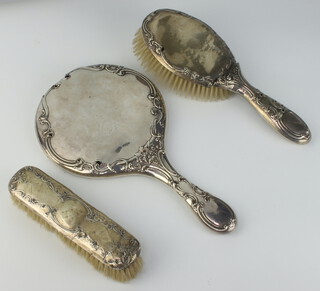 A silver backed hand mirror with repousse decoration Chester 1917, a ditto hair brush Chester 1918 (both a/f) and a silver backed clothes brush 