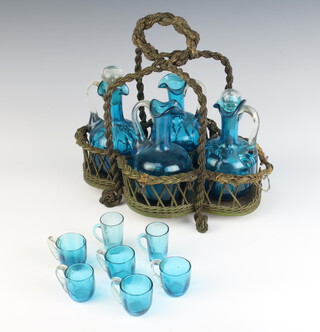 A Continental turquoise glass liqueur set comprising 4 ewers (2 without stoppers), 5 cups and 2 tots with a wickerwork basket