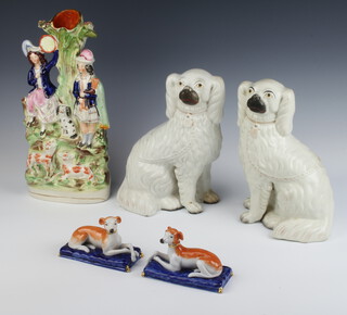 A pair of Victorian style Staffordshire figures of reclining greyhounds on cushions 11cm, a pair of Victorian Staffordshire Spaniels 24cm and a Staffordshire group of 2 figures standing before a tree (restored) 35cm 