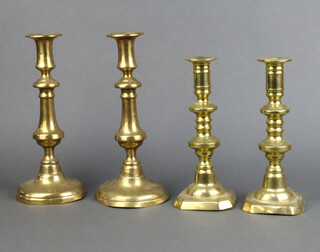 A pair of 19th Century candlesticks with ejectors on circular bases 28cm h (bases dented) together with a pair of 19th Century brass candlesticks with ejectors and shaped bases 23cm h, bases marked 198  
