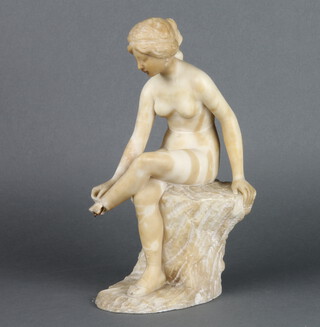 A carved alabaster figure of a seated classical girl, raised on a rocky outcrop 30cm x 10cm x 16cm 