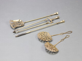 A brass 3 piece fireside companion set comprising tongs, poker and shovel together with 2 pierced brass cream skimmers