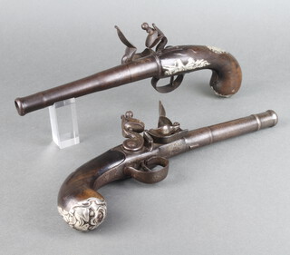 A pair of 18th Century cannon barrelled flintlock pistols with 17cm turn off barrels, having a London proof mark, the base of beech and with walnut stocks inlaid silver trophies and with silver grotesque butt caps