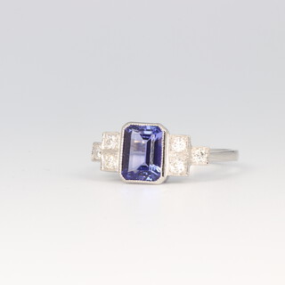 A platinum Art Deco style tanzanite and diamond ring, the centre emerald cut stone 1.5ct, the 3 brilliant cut diamonds to each shoulder 0.3ct, size N, 4.4 grams 