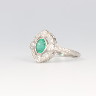 A platinum emerald and diamond cocktail ring, the oval cut centre stone 0.6ct, the brilliant cut diamonds 0.5ct, size N, 4 gram 