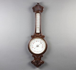 An aneroid barometer and thermometer with porcelain dial marked Lloyd Payne and Mamifl of Manchester, contained in a carved oak wheel case 18cm x 25cm 