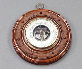 An Edwardian aneroid barometer with enamelled dial, contained in a carved walnut case 22cm diam. 