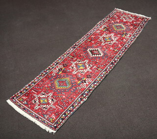 A red, white and blue Afghan runner with 7 stylised medallions to the centre 269cm x 77cm 
