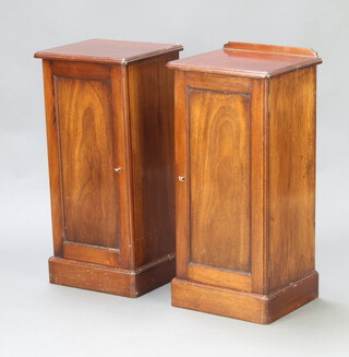 A pair of Edwardian mahogany bedside cabinets, one with raised back (the other is missing), cupboard enclosed by a panelled door, raised on a platform base 79cm h x 36cm x 32cm d 