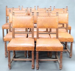 A set of 12 Victorian carved oak framed dining chairs, the seats and backs upholstered in brown rexine and raised on turned and fluted supports with X framed stretcher 97cm h x 47cm w x 46cm d (seat 29cm x 33cm)  