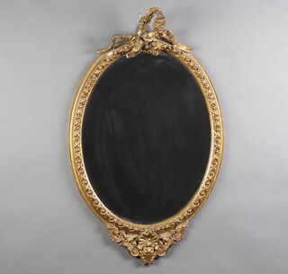 A 19th Century oval plate wall mirror contained in a decorative gilt plaster frame surmounted by a ribbon garland 83cm x 53cm 