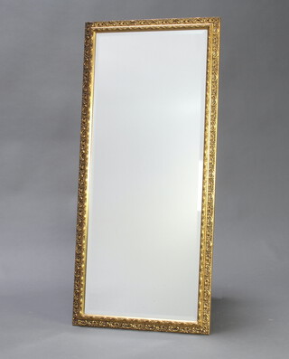 A rectangular bevelled plate mirror contained in a decorative gilt frame 99cm h x 44cm w 