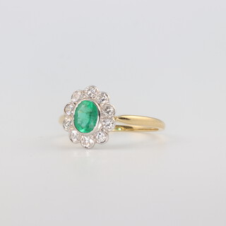 An 18ct yellow gold Edwardian style oval, emerald and diamond cluster ring, the centre oval cut stone approx. 0.65ct, the 10 brilliant cut diamonds approx. 0.5ct, 2.6 grams, size N 1/2