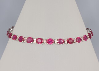 A white metal ruby and diamond bracelet, the 26 treated oval rubies approx. 12.23ct, the 52 brilliant cut diamonds approx. 0.55ct, 8.9 grams, 18cm 
